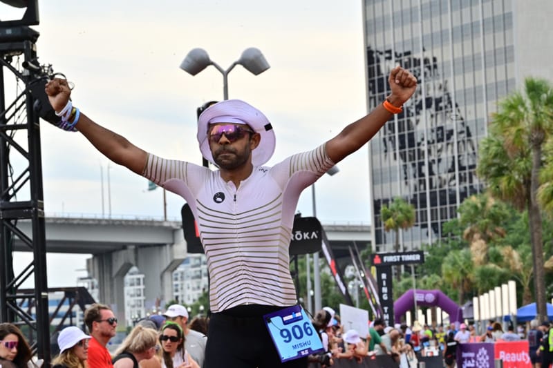 Mishu Biswas raises both arms as he reaches the IRONMAN Jacksonville 2026 finish line
