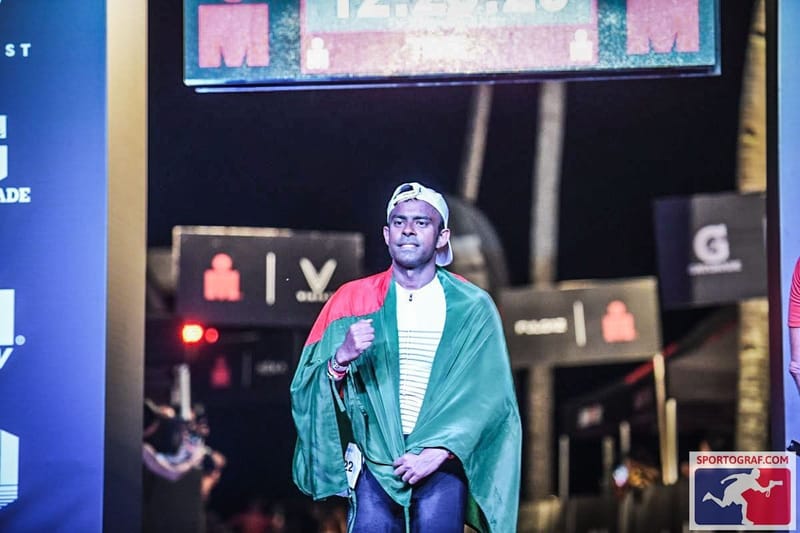 Mishu Biswas wrapped in the flag of Bangladesh in an IRONMAN finish chute